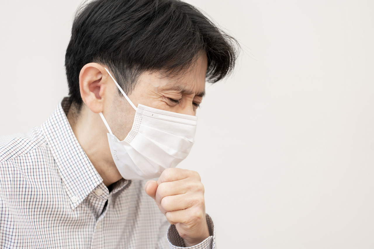 マスクをして、せき込む男性のイメージ画像