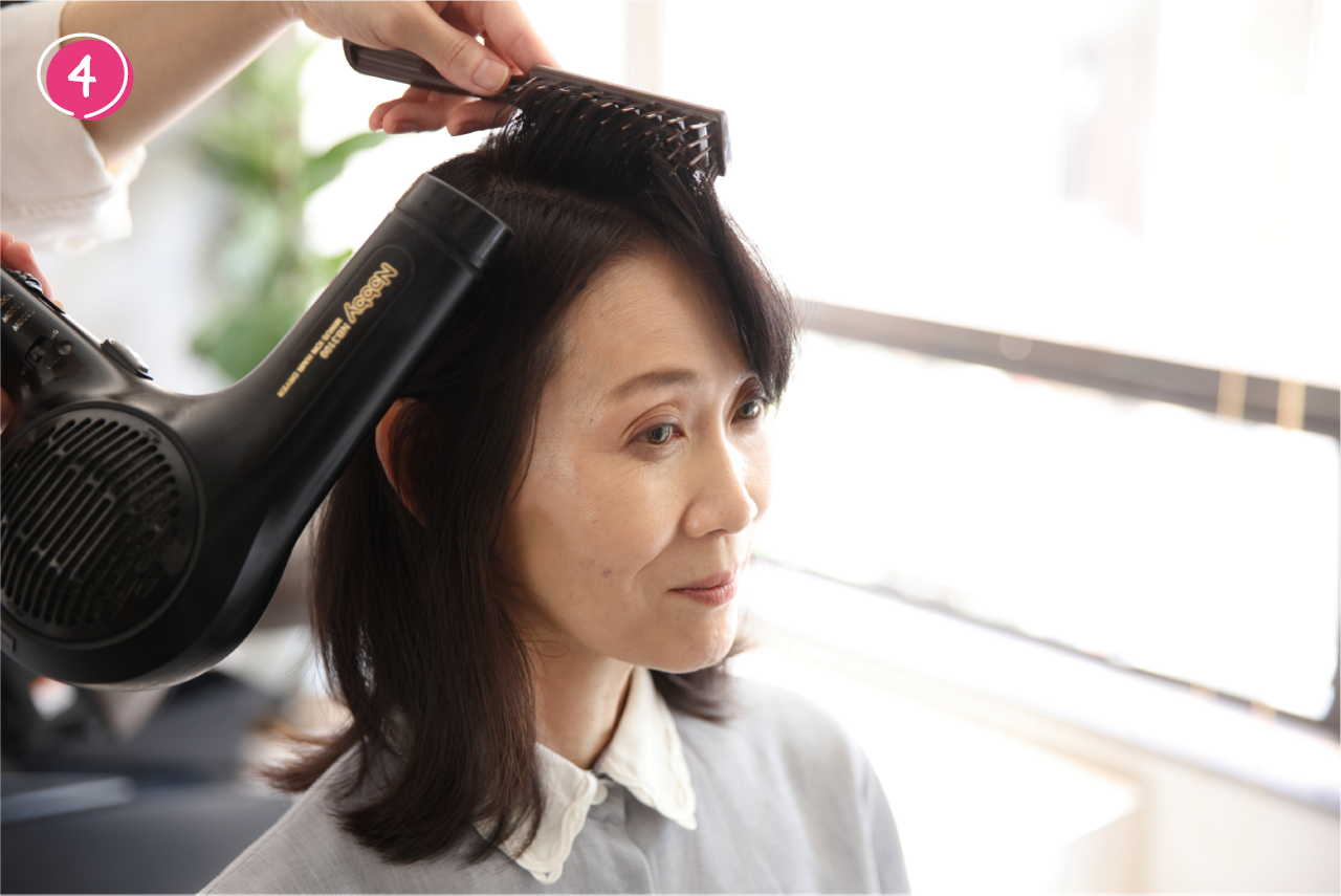 ➃❸の位置でヘアブラシを固定したまま、ドライヤーで熱を当てる。髪に熱が入ったら、ブラシをそのまま外さずに3秒間冷ます（ドライヤーを冷風にして冷ましてもよい）。