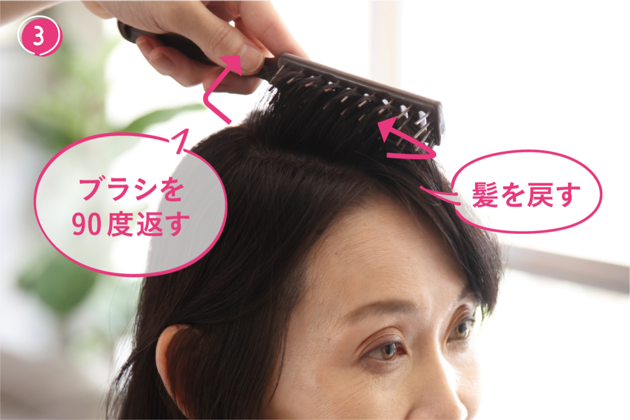 ③ヘアブラシを90度返し、髪を折るようにしながら、分け目に向かって髪を戻す。