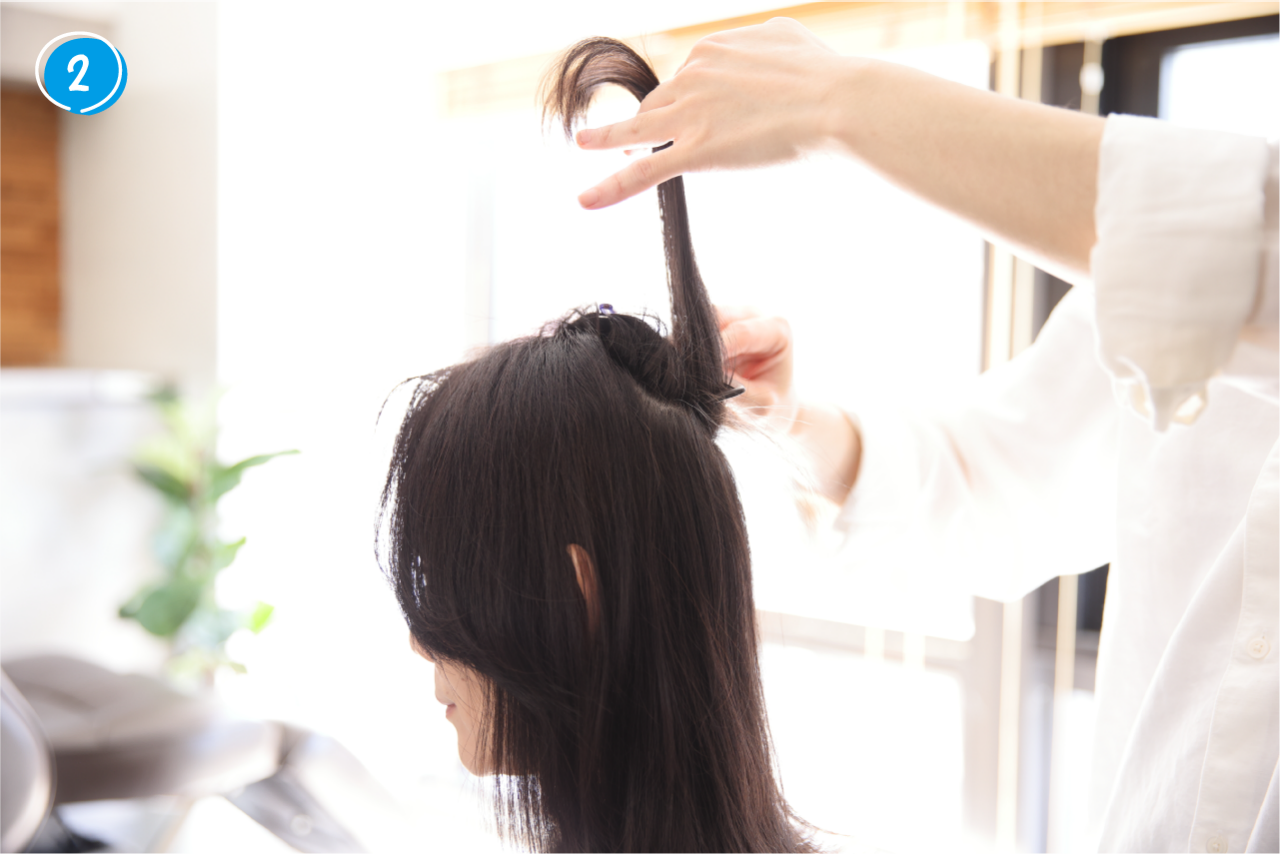 ②仮留めした髪のうち、一番下になる部分の髪をコームでさらに薄く分け取る。残りの髪はピンで留めたままにしておく。