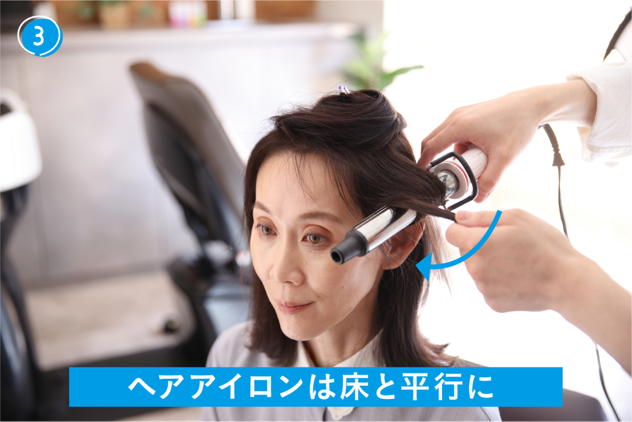 ③挟んだ部分から下の髪を内巻きに巻く。この時、床とヘアアイロンが平行になるように巻いていく。